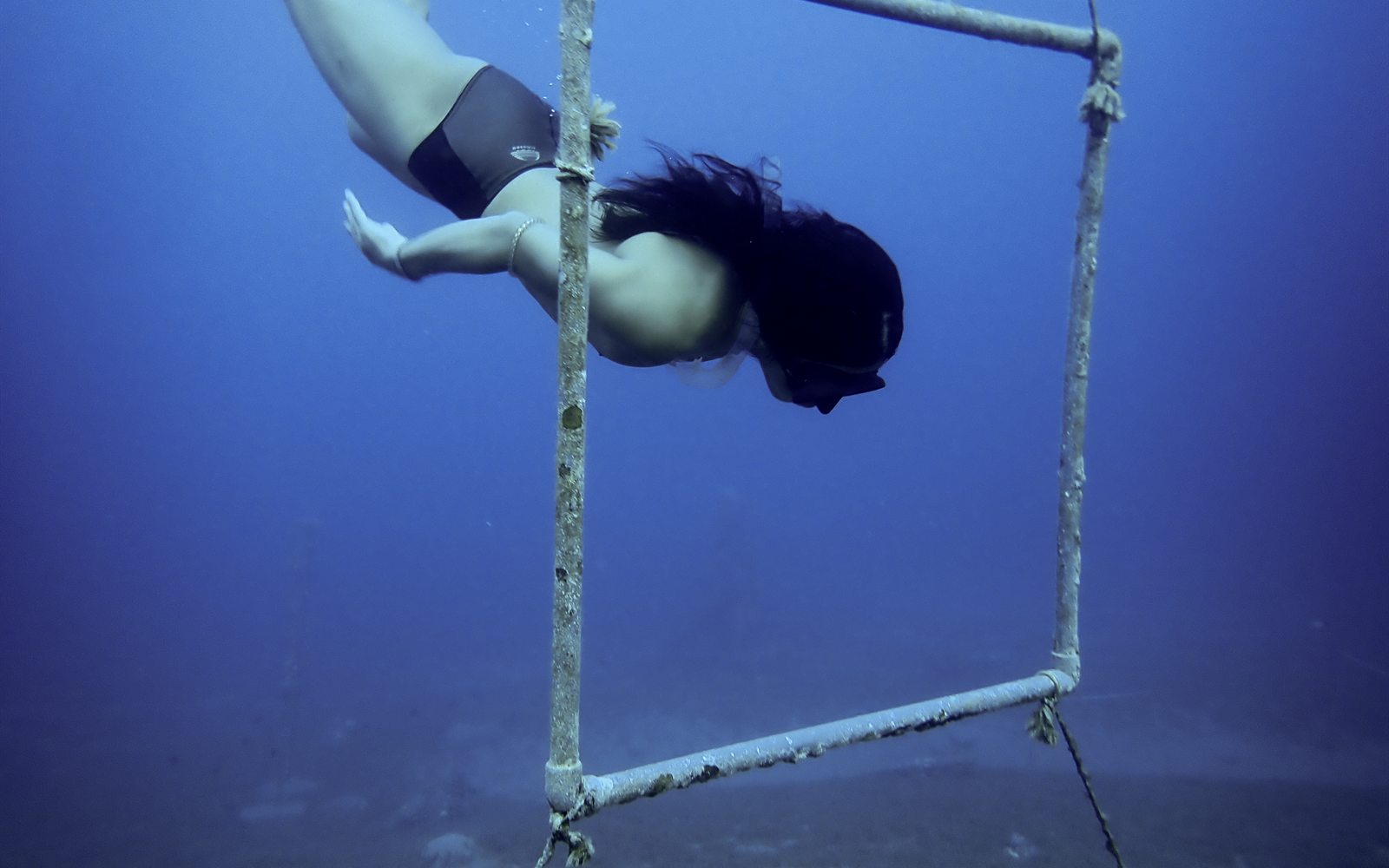 Freediver descending into the deep blue