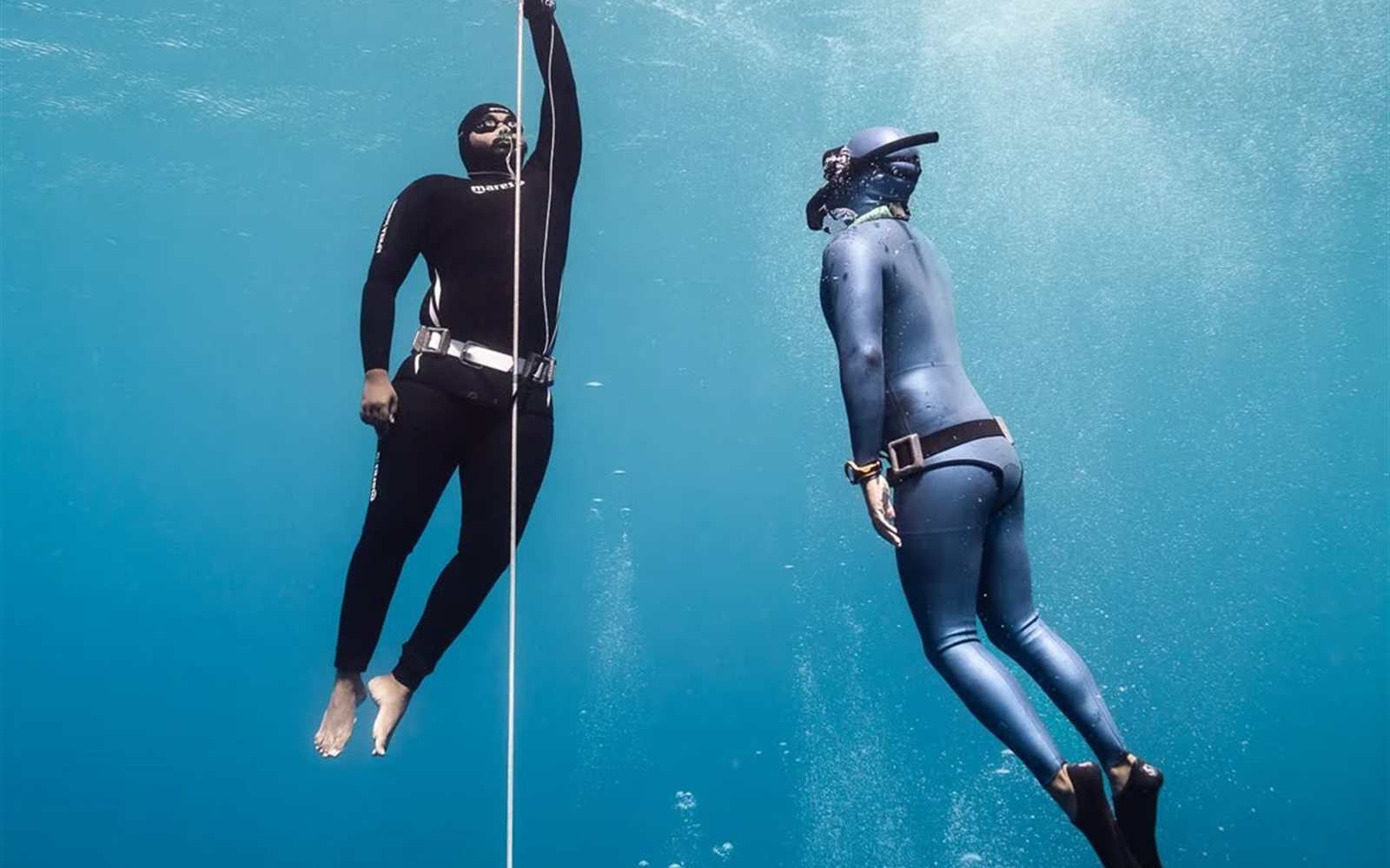 Two freedivers descending a line together