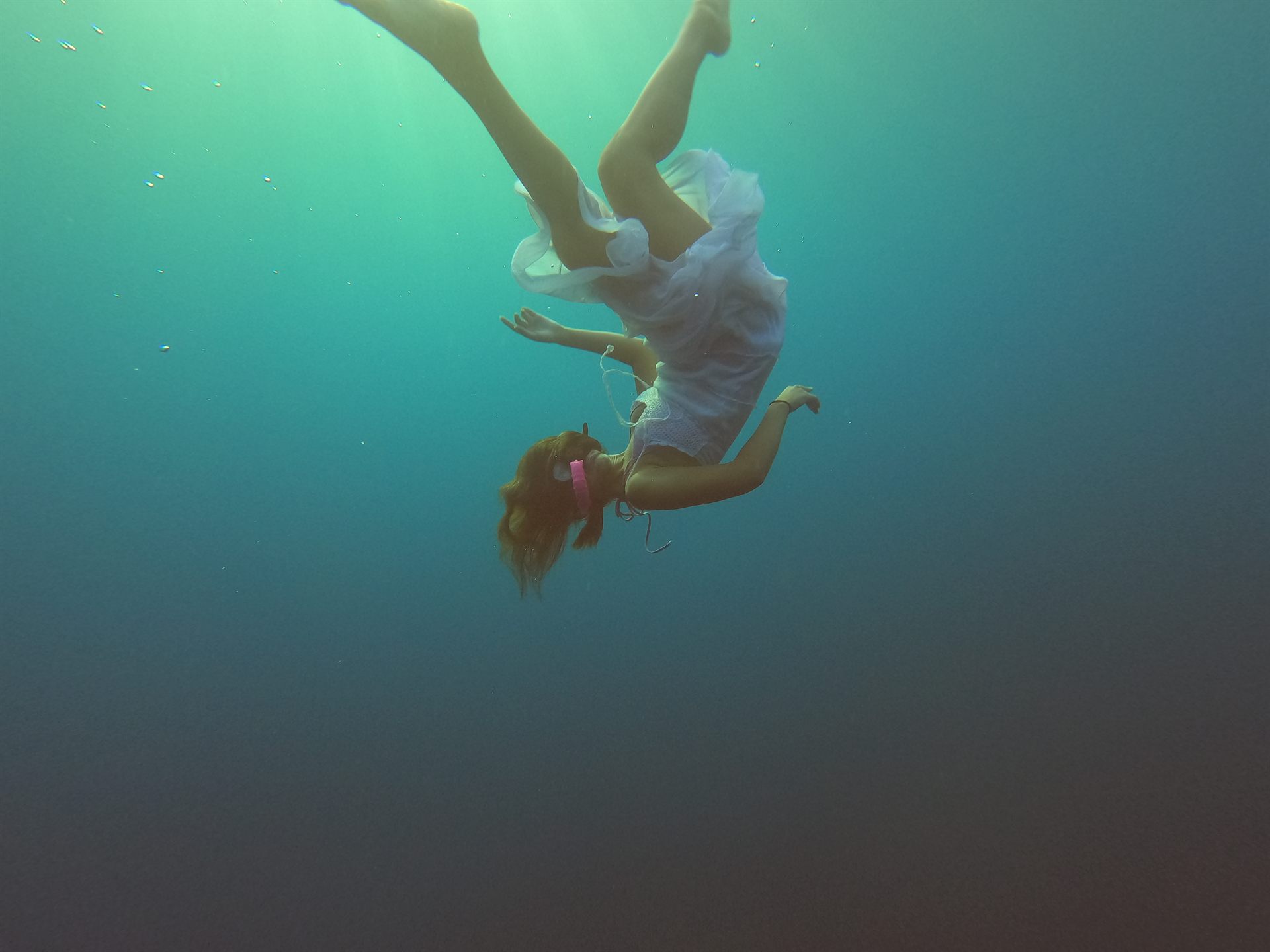 A freediver drifting weightless through sunlit blue water